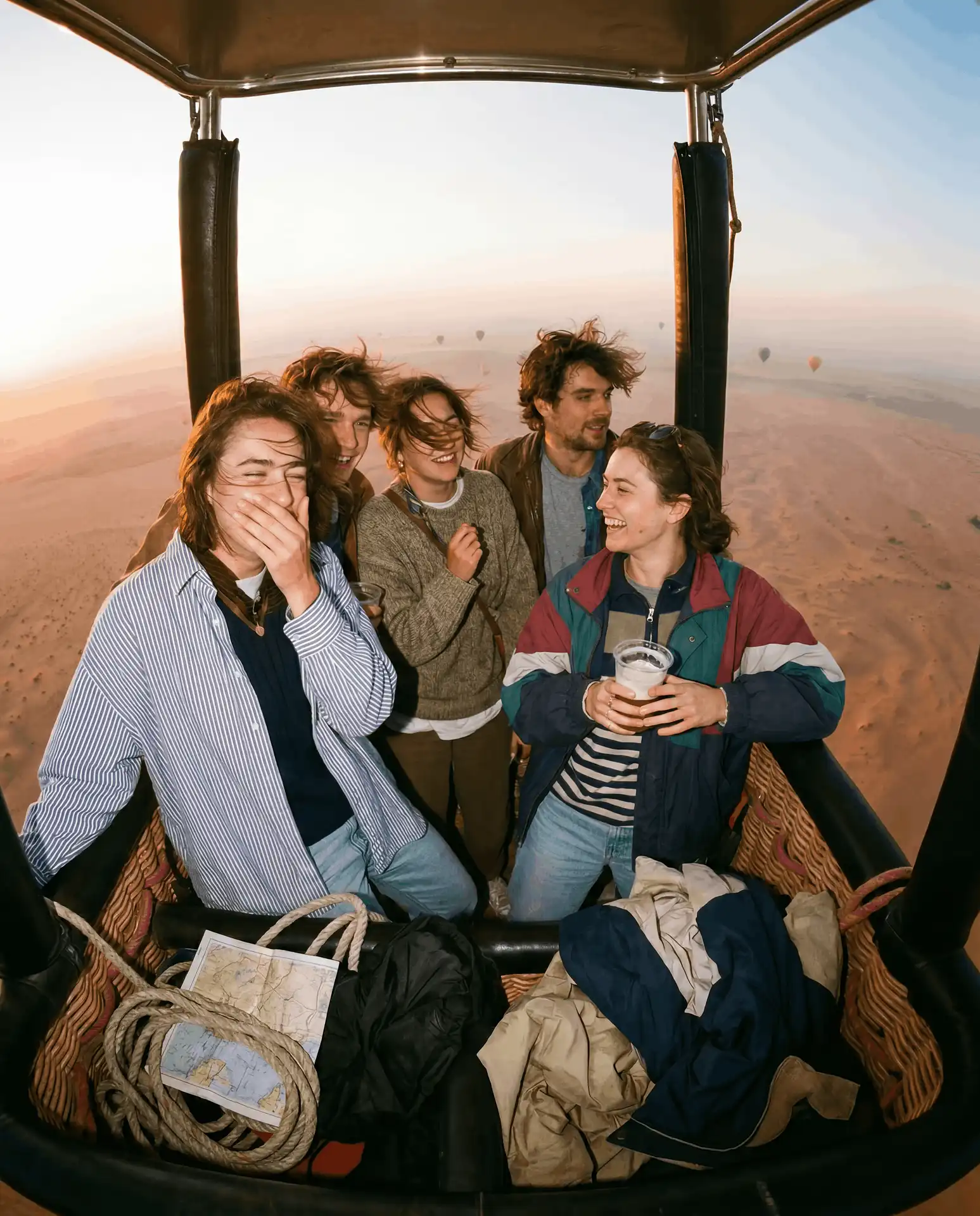 A group of friends laughing together on a sunrise hot air balloon ride